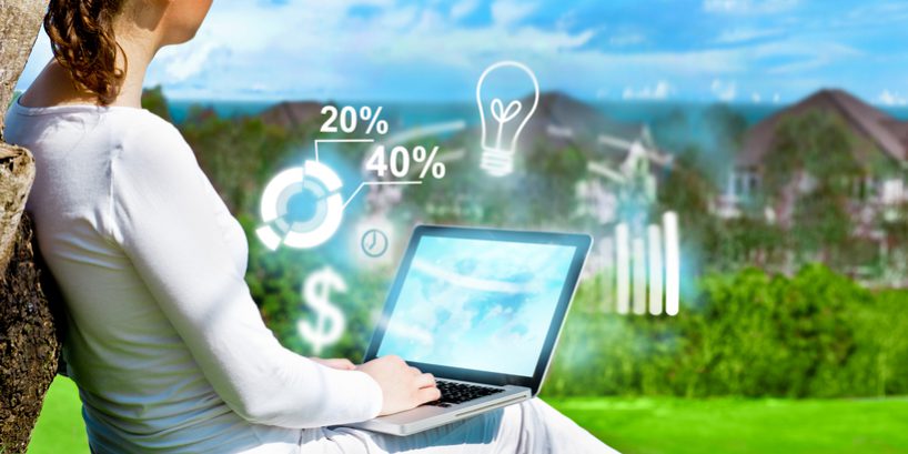 Young beautiful woman sitting under a tree and working with her